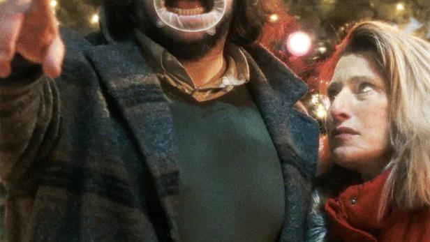 Das Filmplakat für „The Baltimorons“ zeigt einen Mann mit Mundspreizer und eine Frau vor einem Weihnachtsbaum.
