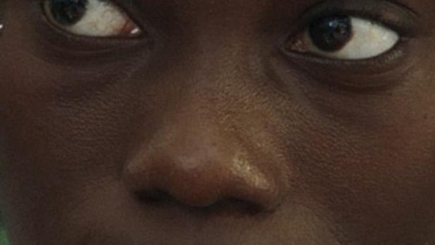 Nahaufnahme vom Gesicht einer jungen, dunkelhäutigen Frau.