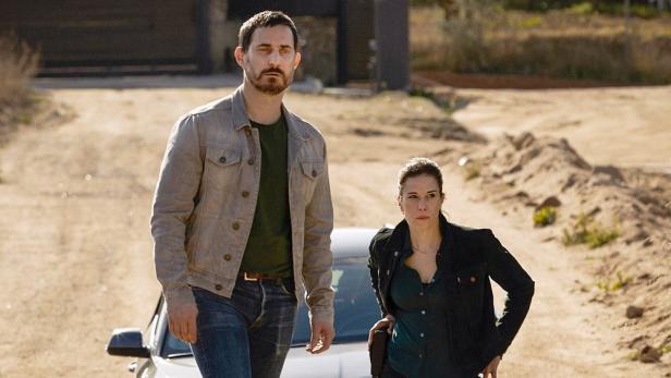Ein Mann und eine Frau stehen vor einem Auto, möglicherweise aus der „Barcelona-Krimi“-Reihe.
