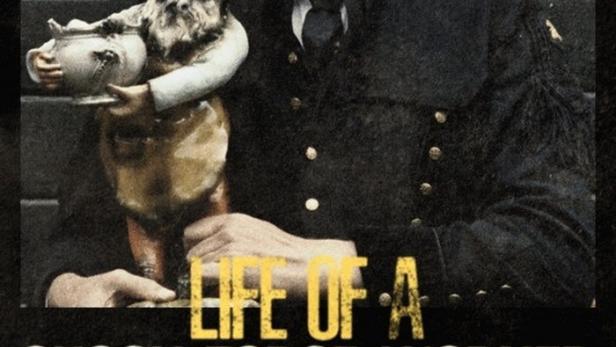 Ein Mann im Kostüm hält eine Gartenzwerg-Figur in der Hand.