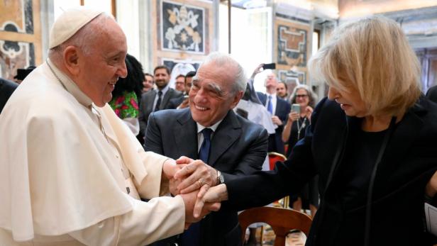 Papst Franziskus schüttelt Martin Scorsese und einer Frau die Hände.