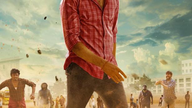 Ein Mann in einem roten Hemd steht vor einer Menschenmenge, im Hintergrund der Titel „Maaman“.