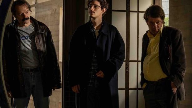 Drei Männer stehen in einem Gebäude mit einem kreisförmigen Eingang.