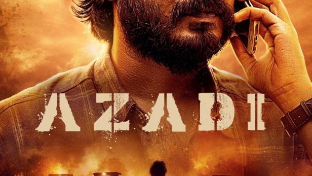 Ein Mann telefoniert vor einem Hintergrund aus brennenden Fahrzeugen und Menschen.