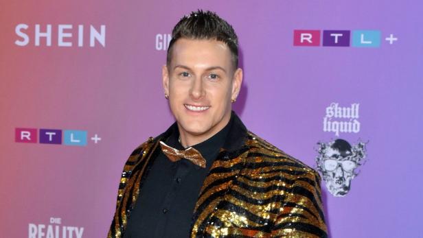 Calvin Kleinen trägt ein goldenes Paillettensakko auf dem roten Teppich.