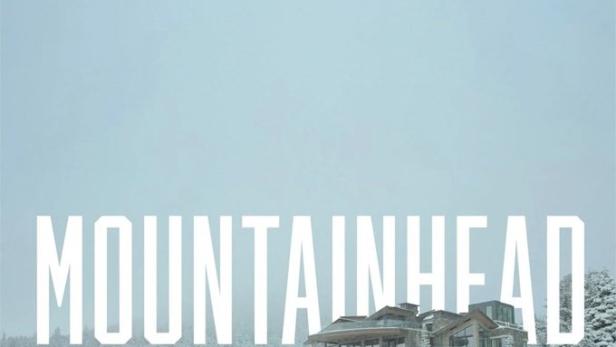 Ein modernes Haus steht auf einem schneebedeckten Hügel, umgeben von Bäumen.