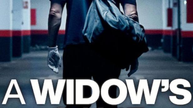 Ein Mann mit einer Tasche geht in „A Widow's Game“ in einer Tiefgarage.