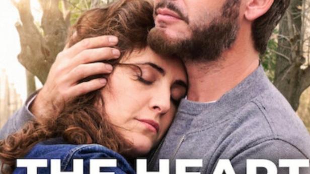 Ein Mann und eine Frau umarmen sich innig vor einer Baumkulisse.