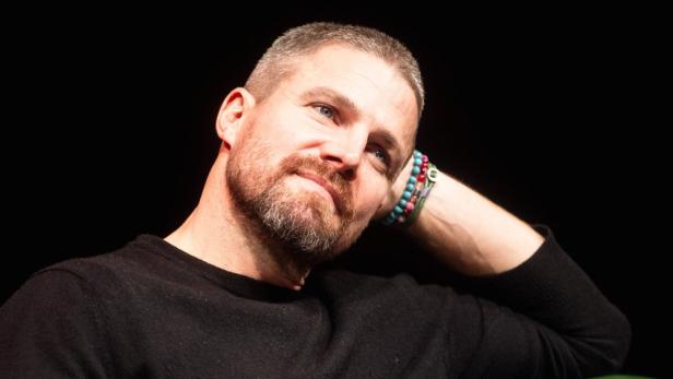 Stephen Amell posiert mit dem Kopf in seiner Hand.