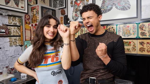 Eine Frau und ein Mann präsentieren ihre neuen Tattoos in einem Tattoo-Studio in London.