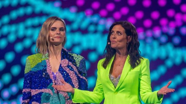 Zwei Frauen, vermutlich Brugger und Studer, stehen vor einem farbenfrohen Hintergrund auf einer Bühne.