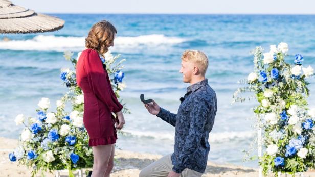 Ein Mann macht seiner Partnerin am Strand einen Heiratsantrag.