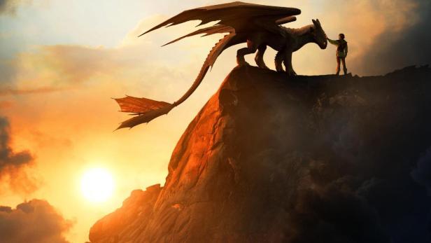 Ein Junge steht bei Sonnenuntergang einem Drachen auf einem Felsen gegenüber, im Hintergrund der Filmtitel „Drachenzähmen“.