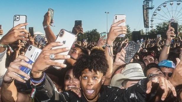 Eine Menschenmenge filmt und fotografiert ein Konzert mit ihren Handys.