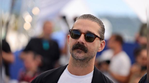 Shia LaBeouf mit Sonnenbrille und Schnurrbart blickt nach oben.