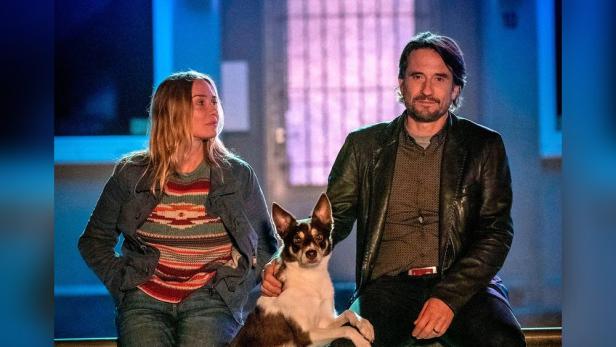 Ein Mann und eine Frau sitzen mit einem Hund zusammen.