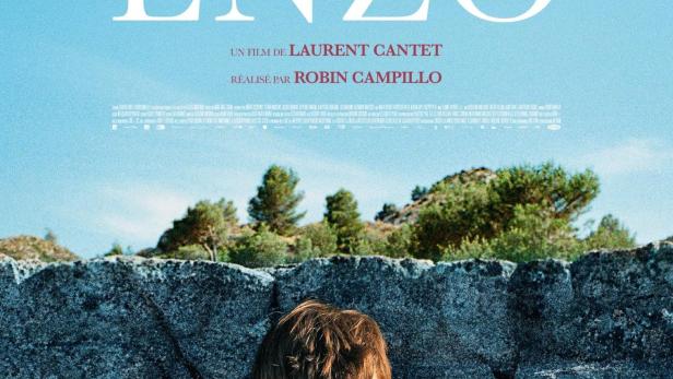 Ein junger Mann telefoniert vor einer Steinmauer; Filmplakat für „Enzo“.