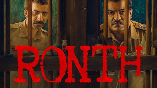 Zwei Polizisten blicken durch die Gitterstäbe einer Gefängniszelle, im Vordergrund der Titel „Ronth“.