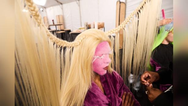 Ein Model mit rosa Gesichtsbemalung und blonden Haaren wird für „Germany’s Next Topmodel“ gestylt.