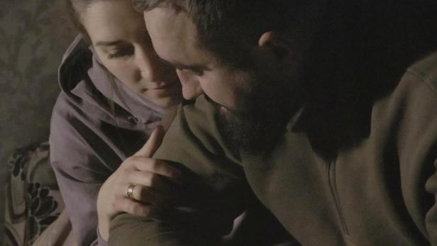 Ein Paar umarmt sich innig in einem dunklen Raum.