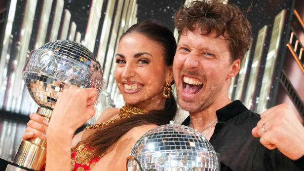 Ekaterina Leonova und ein Mann mit Discokugeln feiern einen Sieg.