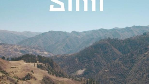 Ein Erwachsener umarmt ein Kind auf einem Felsen mit Blick auf eine Berglandschaft. Im Vordergrund steht der Text „Runa Simi“.