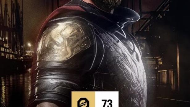 Ein Mann mit Bart und Krone trägt eine Rüstung vor einer dunklen Stadtkulisse.