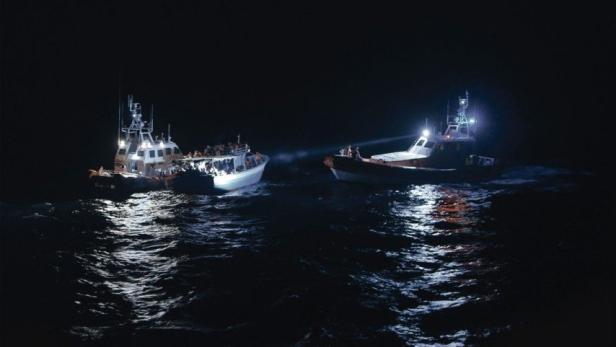 Das Filmplakat zu „Lampedusa im Winter“ zeigt zwei Schiffe auf dunklem Wasser.