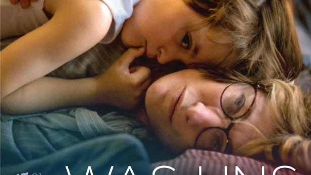 Das Filmplakat zu „Was uns verbindet“ zeigt eine Mutter und ihr Kind, die eng aneinander gekuschelt liegen.