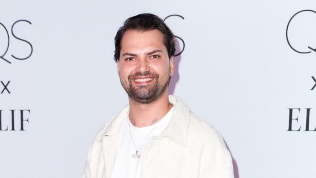 Jimi Blue Ochsenknecht lächelt vor einem weißen Hintergrund.