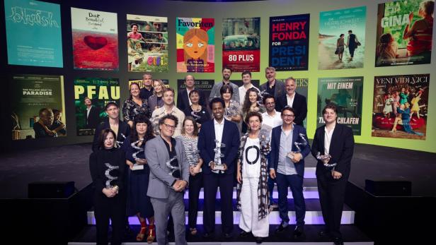 Preisträger des Österreichischen Filmpreises 2025 posieren vor Filmplakaten.