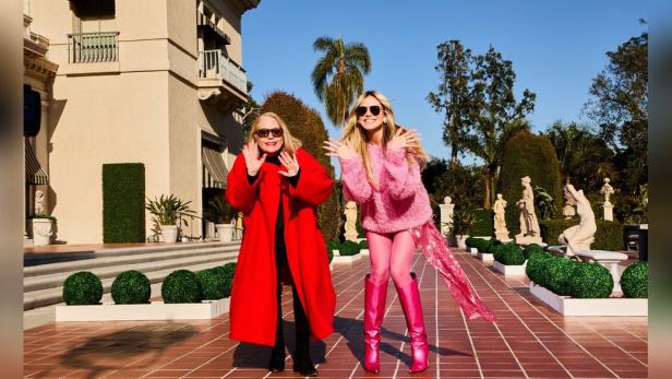 Heidi Klum und ihre Mutter Erna posieren vor einer Villa mit Garten.