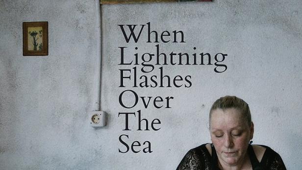 Das Filmplakat für „When Lightning Flashes Over The Sea“ zeigt eine Frau an einem Tisch.