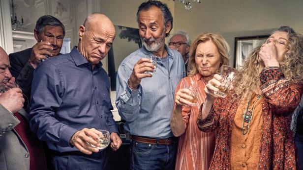 Eine Gruppe von Menschen verzieht das Gesicht, nachdem sie aus Gläsern getrunken haben.