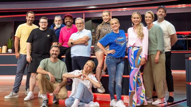 Eine Gruppe von Prominenten posiert für ein Foto in einem Fernsehstudio.