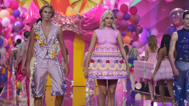 Models präsentieren extravagante Mode, darunter ein Kleid in Form einer Geburtstagstorte.