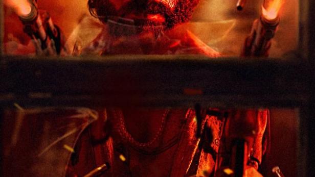 Ein Mann mit Bart und blutigem Gesicht zielt mit zwei Pistolen durch ein zerbrochenes Fenster.