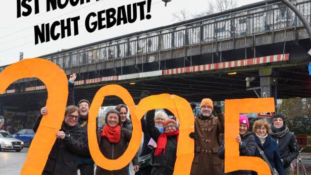 Eine Gruppe von Menschen hält orangefarbene Pappzahlen „2025“ unter einer Brücke.