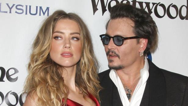 Amber Heard und Johnny Depp posieren zusammen auf einem roten Teppich.