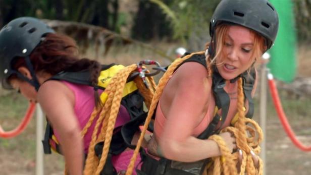 Zwei Frauen mit Helmen und Seilen nehmen an einer Reality-TV-Show teil.