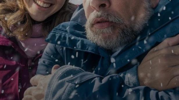 Ein Mann und eine junge Frau umarmen sich im Schnee; Filmposter für „Almost Family“.