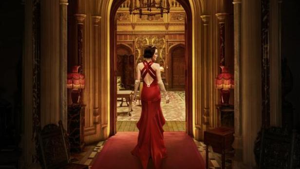 Eine Frau in rotem Kleid steht in einem prunkvollen Saal von Downton Abbey.