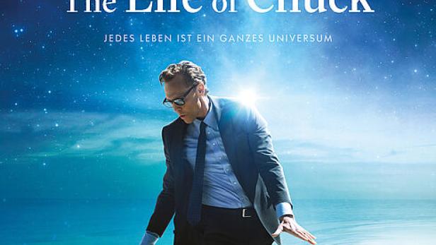 Das Filmplakat für „The Life of Chuck“ zeigt Tom Hiddleston vor einem sternenklaren Himmel und Meer.