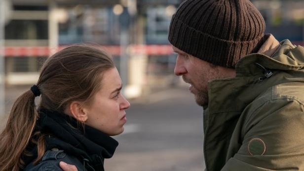 Eine junge Frau und ein Mann in Winterkleidung stehen sich konfrontativ gegenüber.