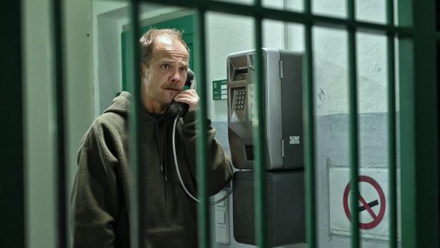 Ein Mann telefoniert in einer Gefängniszelle.