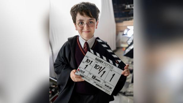 Ein Kind, verkleidet als Harry Potter, hält eine Filmklappe des Films in der Hand.