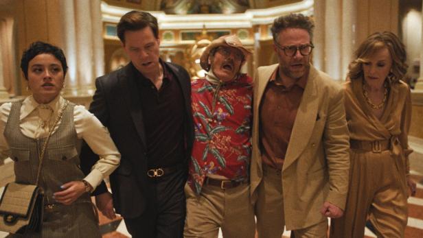 Eine Gruppe von fünf Personen, möglicherweise Schauspieler, steht in einer opulenten Hotellobby.