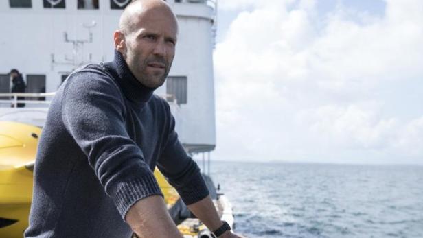 Jason Statham auf einem Schiff mit Blick auf das Meer.