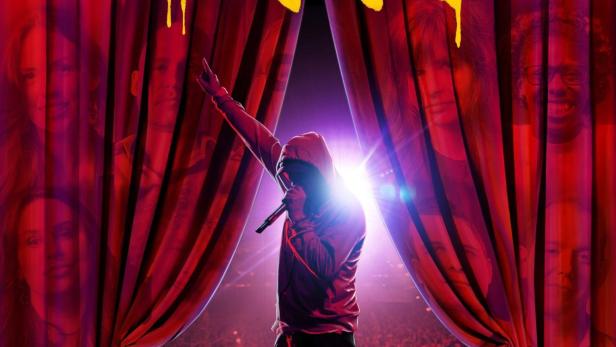 Ein Rapper steht auf einer Bühne vor einem Publikum, im Hintergrund der Schriftzug „Stans“.