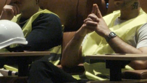 Zwei Bauarbeiter sitzen in einem Kinosaal und machen eine Pause.